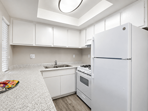 Hemet multi-family for rent - A white kitchen with a refrigerator, sink, and stove.