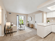 Hemet multi-family for rent - A well-lit, spacious living room with a white sofa, a wooden side table, and a large window.