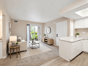 Hemet multi-family for rent - A well-lit, spacious living room with a white sofa, a wooden side table, and a large window.