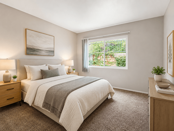 Hemet multi-family for rent - A bedroom with a large bed and a window overlooking a garden.