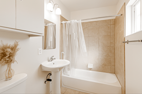 Downey multi-family for rent - A white bathroom with a white tub, sink, and shower curtain.