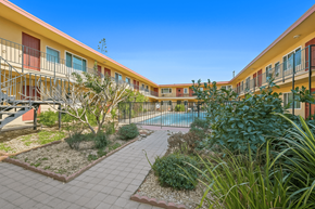 Downey multi-family for rent - A sunny day at a residential complex with a pool and a well-maintained garden.