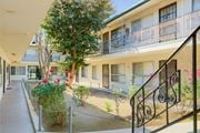 Lynwood multi-family for rent - A balcony with a black railing and a tree in front of a building.