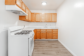 Azusa multi-family for rent - A kitchen with wooden cabinets and a white stove top oven.