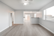 Rialto multi-family for rent - A spacious room with a ceiling fan and light, hardwood flooring, and a large window with blinds.