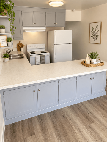 Claremont multi-family for rent - A kitchen with a white counter top and grey cabinets.