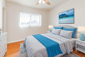 Downey multi-family for rent - A bedroom with a bed, nightstand, and a painting on the wall.
