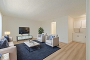 Pico Rivera multi-family for rent - A living room with a white couch, a white chair, a black coffee table, and a television.