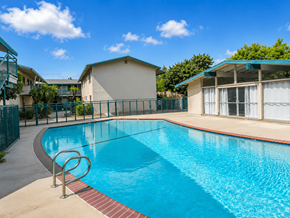San Gabriel apartment for rent - A swimming pool surrounded by a fence and a building in the background.