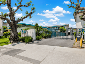 San Gabriel apartment for rent - A tree stands in front of a white building with a blue roof.