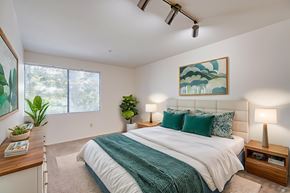 Pomona apartment for rent - A bedroom with a large bed and a painting on the wall.