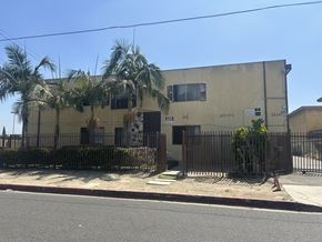 Compton multi-family for rent - A building with a fence and palm trees in front.