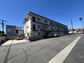 Wilmington multi-family for rent - A parking lot with a white building and a car parked in front.