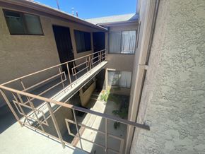 Gardena multi-family for rent - A balcony with a metal railing and a small garden area.