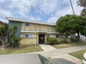 Harbor City multi-family for rent - A building with a green roof and a yellow wall with a red door.