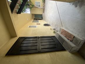 Harbor City multi-family for rent - A black door with a metal handle is in the center of a concrete wall.