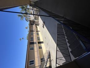 Harbor City multi-family for rent - A tall building with a balcony and a tree in the background.