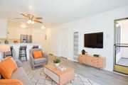 Paramount apartment for rent - A living room with a grey couch, orange pillows, a pink coffee table, and a television.