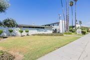 El Monte apartment for rent - A building with a wall covered in graffiti is surrounded by a green lawn and palm trees.