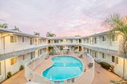 Bellflower multi-family for rent - A swimming pool is surrounded by a fence and is in front of a building.