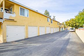 Corona multi-family for rent - A street view of a residential area with apartment buildings and parked cars.