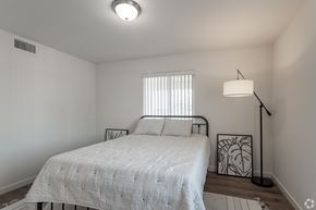 San Bernardino multi-family for rent - A bedroom with a bed, a lamp, and a window with blinds.