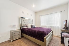 Canoga Park multi-family for rent - A bedroom with a purple bedspread and a white bed frame.