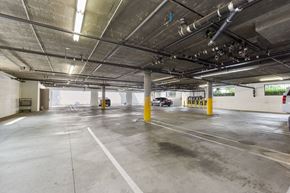 Canoga Park multi-family for rent - A spacious parking garage with concrete floors and yellow bollards.