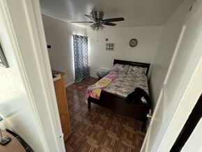 Maywood multi-family for rent - A bedroom with a bed, dresser, and ceiling fan.