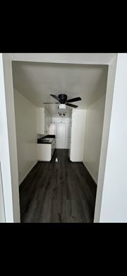 Pomona apartment for rent - A long hallway with a ceiling fan and a white door at the end.
