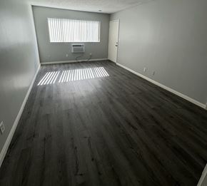 Pomona apartment for rent - A room with wooden flooring and a window with blinds.
