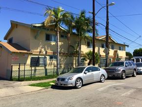 Compton multi-family for rent - A silver car is parked in front of a yellow house with a black fence.