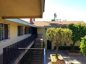 Compton multi-family for rent - A tree in a planter is in the foreground of a building with a balcony.