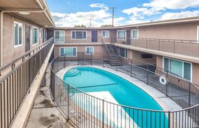 Long Beach multi-family for rent - A small pool in a courtyard surrounded by a metal fence.