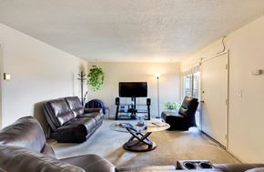 Long Beach multi-family for rent - A living room with a black leather couch, a black chair, a black coffee table, and a flat screen TV.