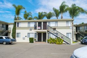 Los Angeles multi-family for rent - A blue car is parked in front of a building with a white facade and a balcony.