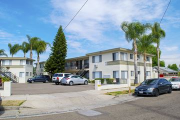 Los Angeles multi-family for rent - A residential street with cars parked on the side and apartment buildings in the background.