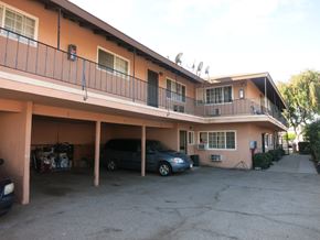 Azusa multi-family for rent - A carport with a black car and a blue car parked in it.
