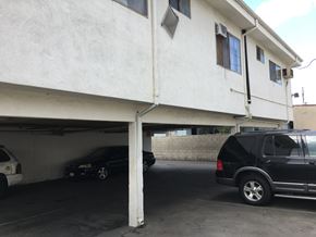 North Hollywood multi-family for rent - A black car is parked in a garage under a white building.