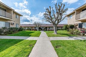 Rowland Heights multi-family for rent - a walkway between two apartment buildings with grass and trees at Colima Terrace Apts, Rowland Heights, 91748