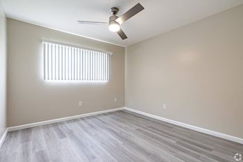 An empty living room with wood floors and a ceiling fan
