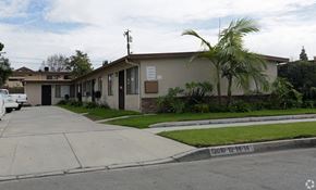 Norwalk multi-family for rent - A house with a driveway and a palm tree in front.