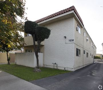 Van Nuys multi-family for rent - A white building with a red tile roof and a tree in front of it.