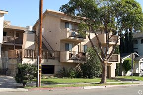 Long Beach multi-family for rent - A tree in front of a building with a balcony.