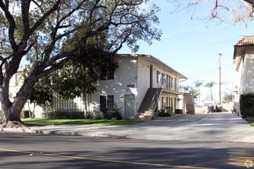 Whittier multi-family for rent - A tree is in front of a white building.