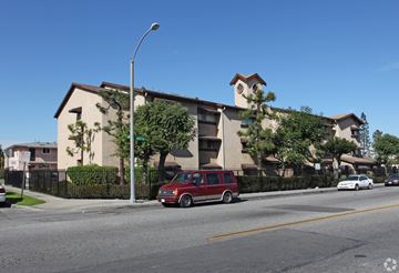 South Gate multi-family for rent - A red van is parked on the side of a street in front of a building.