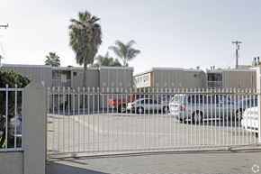 Bellflower multi-family for rent - A gate with the numbers 92609254 on it blocks the view of a parking lot.