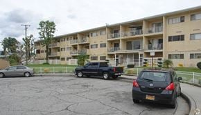 Covina multi-family for rent - A black car is parked in a parking lot in front of a building.