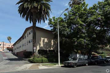 Los Angeles multi-family for rent - A palm tree stands in front of a tan building with a black truck parked in front of it.