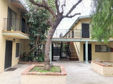 Lynwood multi-family for rent - A tree in front of a building with a black gate.